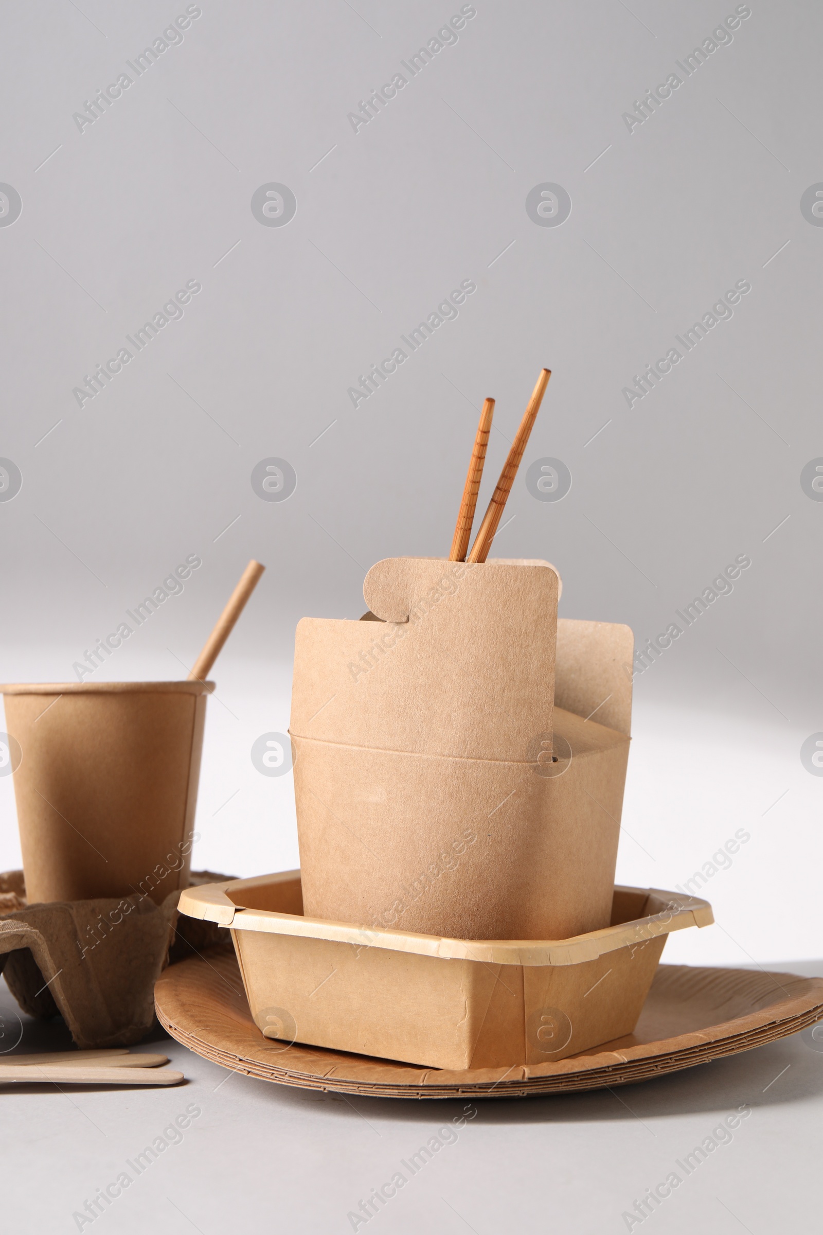 Photo of Eco friendly food packaging. Paper containers and tableware on light background