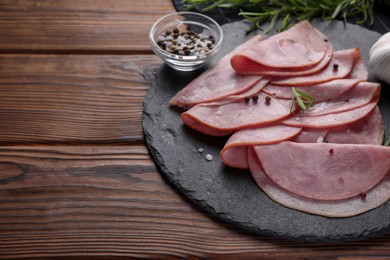 Photo of Tasty ham with rosemary, sea salt and peppercorns on wooden table. Space for text