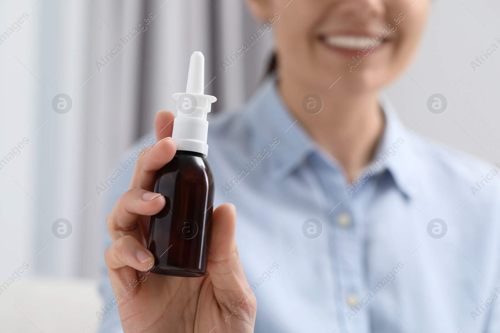 Photo of Woman holding nasal spray bottle indoors, closeup. Space for text