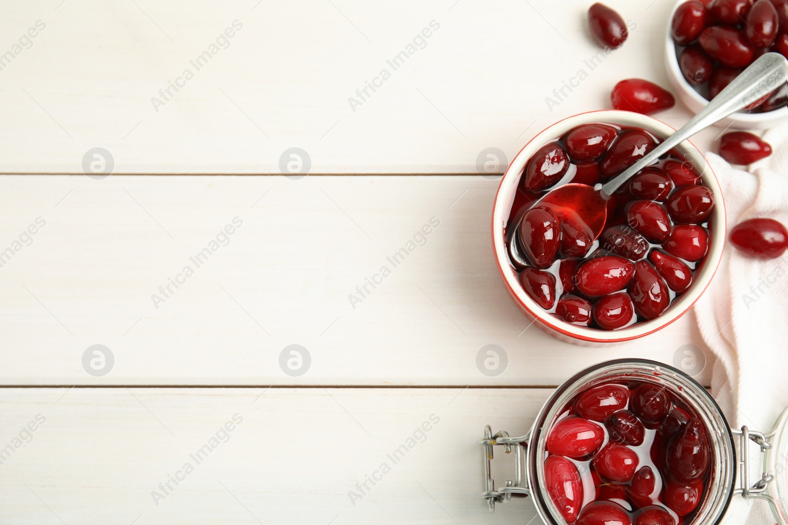 Photo of Delicious dogwood jam with berries on white wooden table, flat lay. Space for text