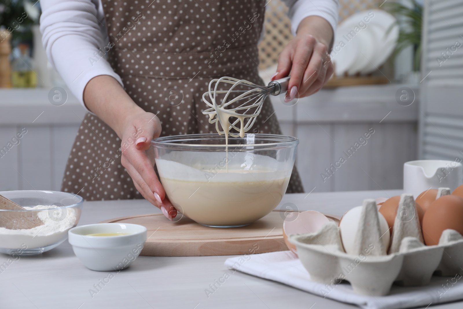 Photo of Woman making dough with whisk in bowl at table, closeup