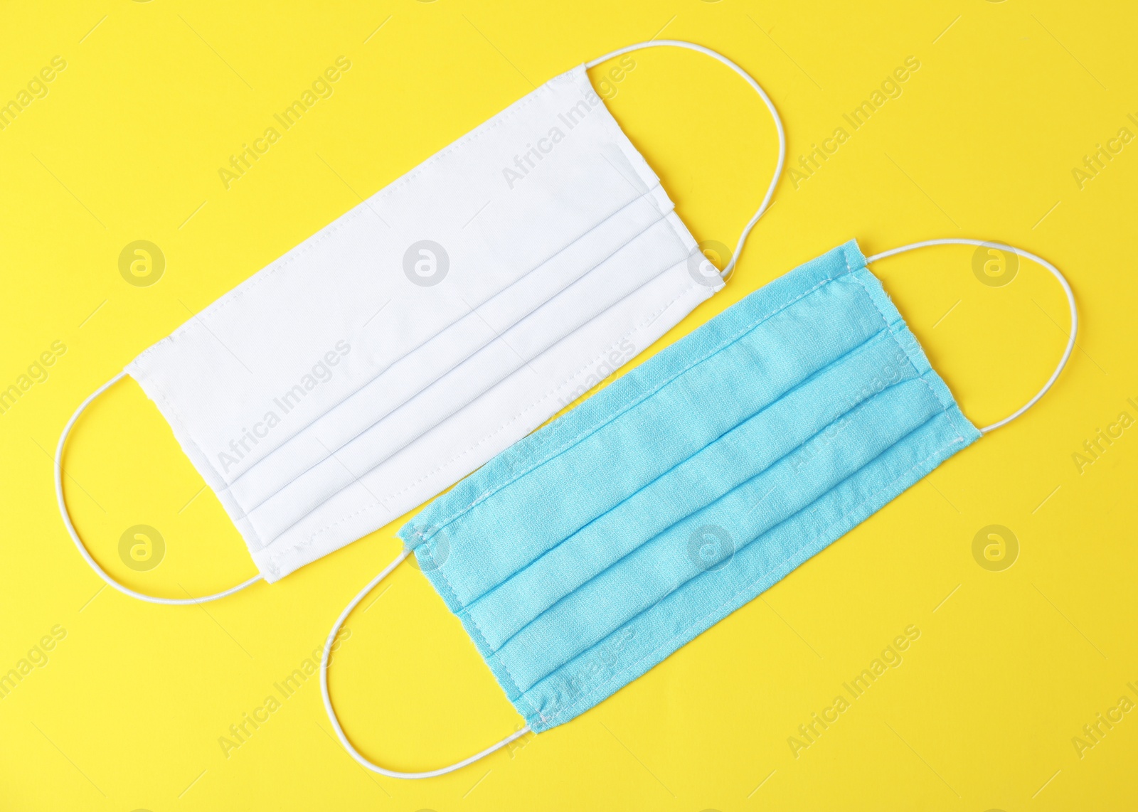 Photo of Homemade protective face masks on yellow background, flat lay