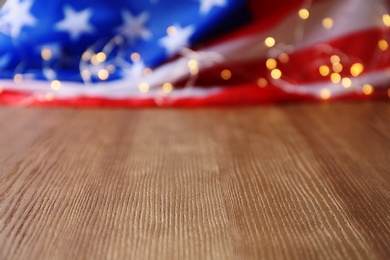 Photo of Blurred American flag and garland on wooden table. Space for text