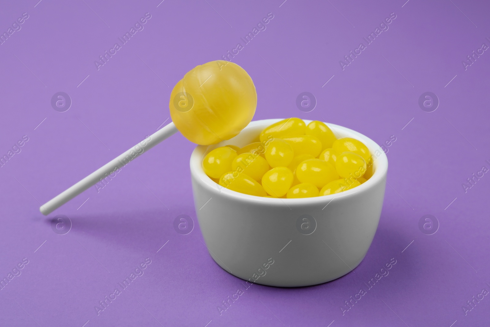 Photo of Different lemon flavored candies on purple background