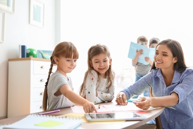 Photo of Cute little children with teacher in classroom at school