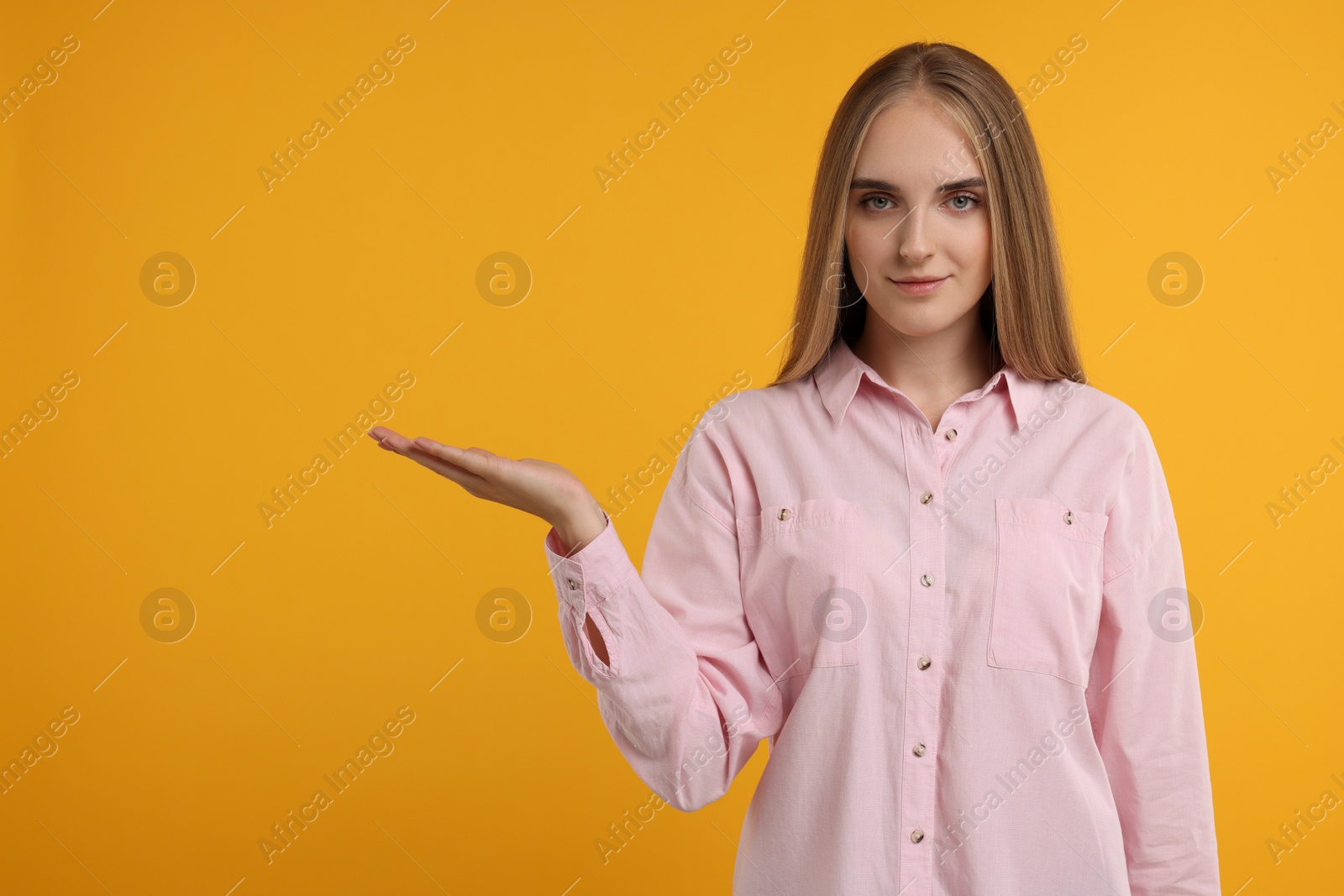 Photo of Special promotion. Young woman showing something on orange background, space for text