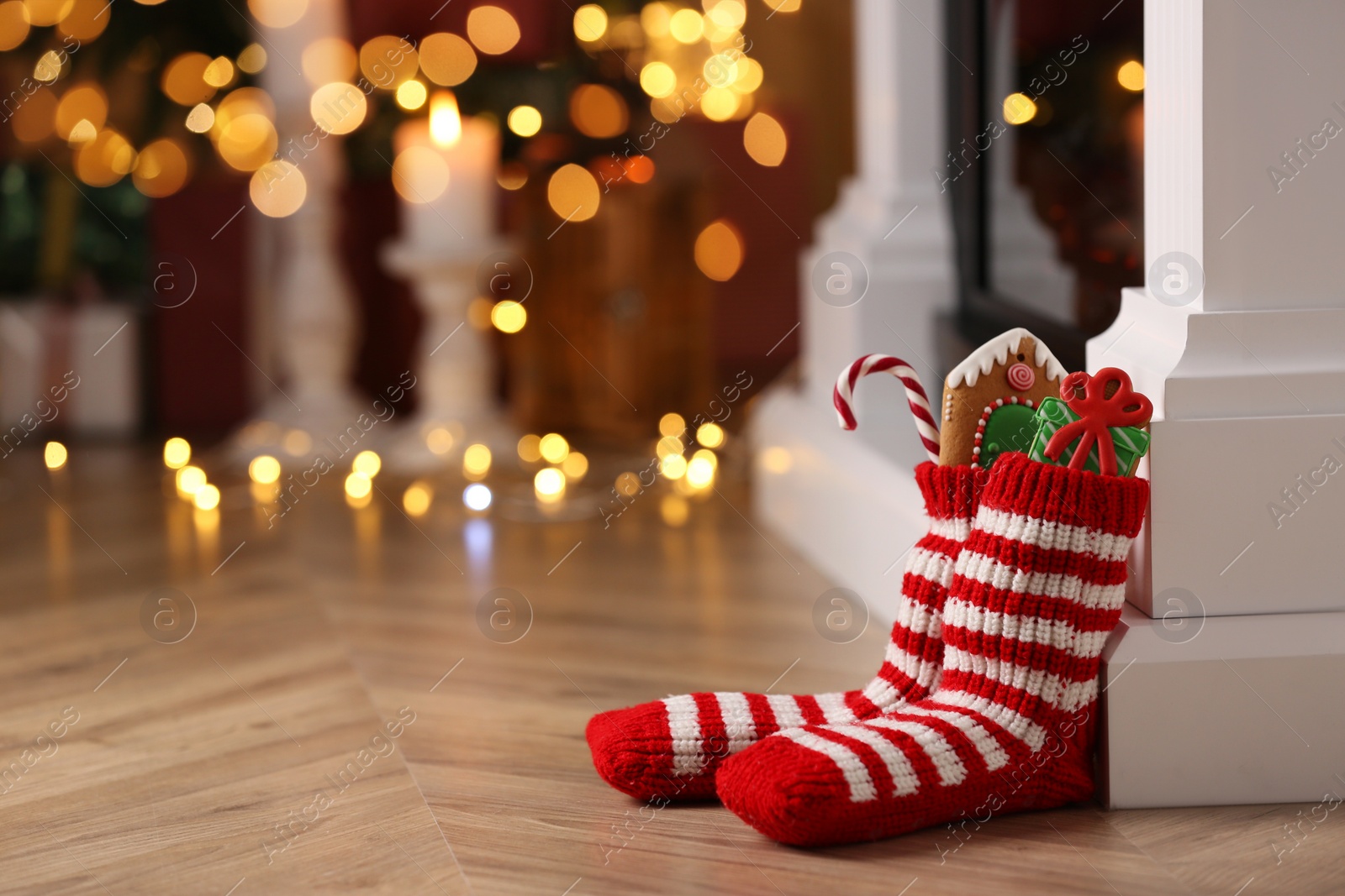 Photo of Socks filled with sweets on floor in room, space for text. Saint Nicholas Day