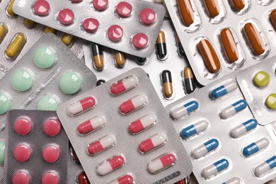 Many blisters with different pills as background, top view