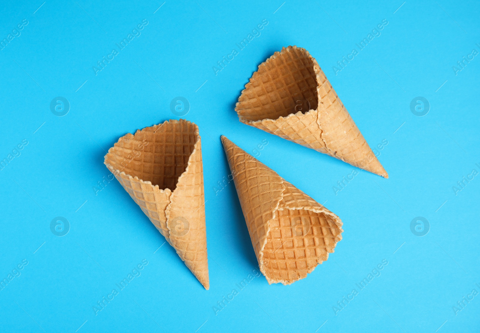 Photo of Waffle empty ice cream cones on color background, flat lay