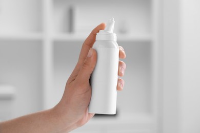 Photo of Woman holding nasal spray bottle indoors, closeup