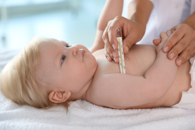 Photo of Pediatrician checking baby's temperature, closeup. Health care