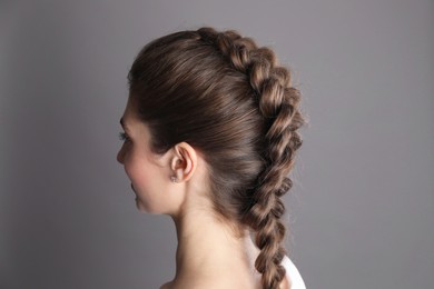 Woman with braided hair on grey background