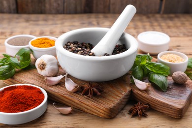 Photo of Mortar with pestle and different spices on wooden table