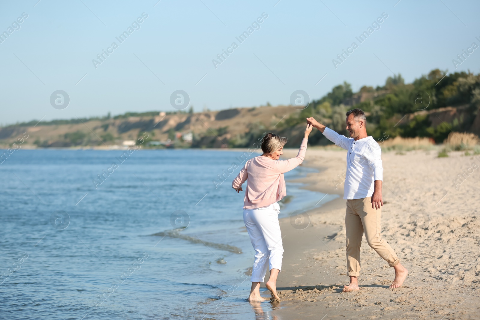 Photo of Happy mature couple dancing at beach on sunny day