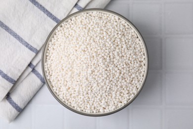 Tapioca pearls in bowl and towel on white tiled table, top view