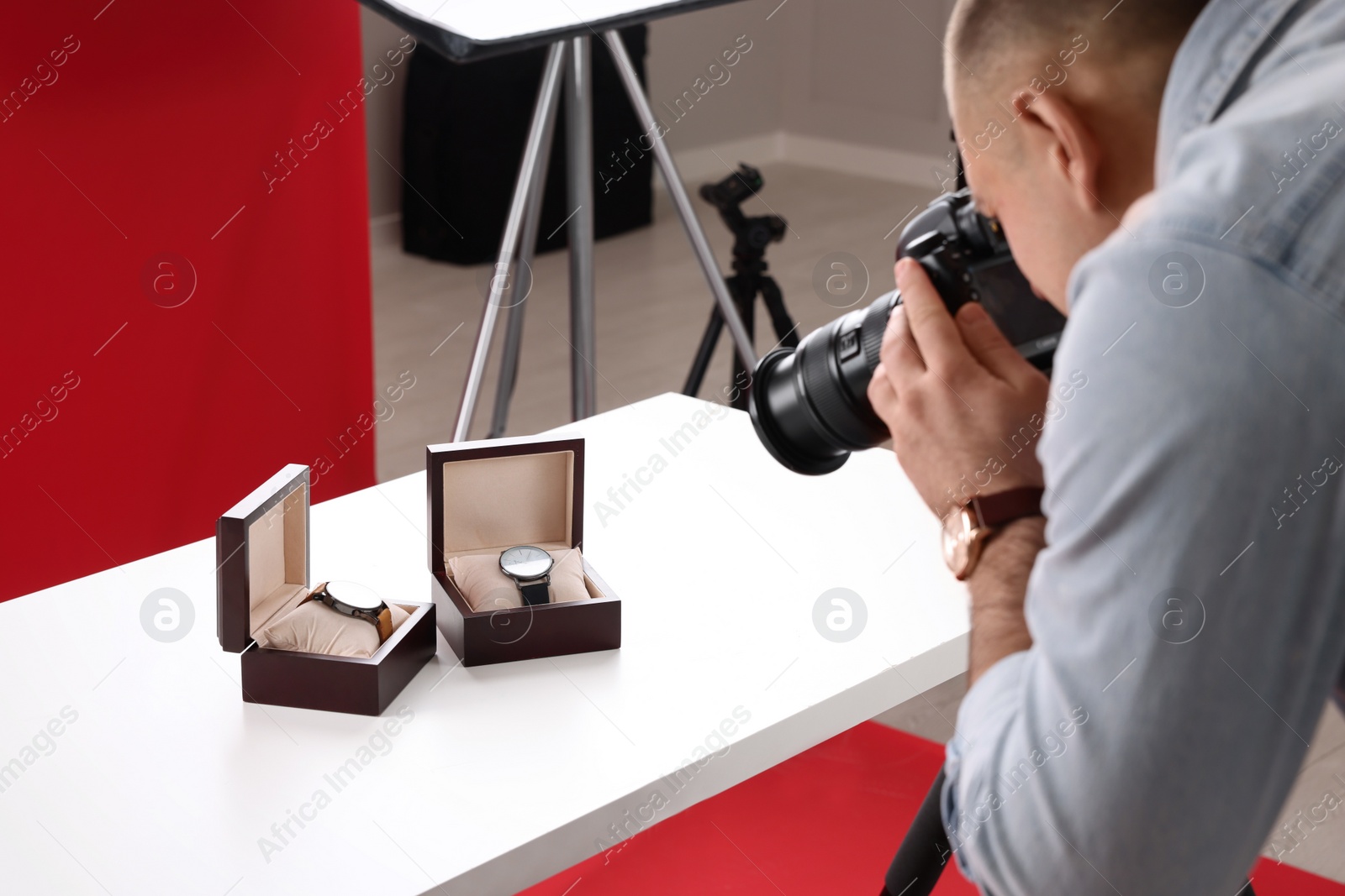 Photo of Professional photographer taking picture of expensive wristwatches in studio, focus on accessories