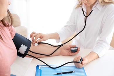 Photo of Female doctor measuring blood pressure of overweight woman in clinic