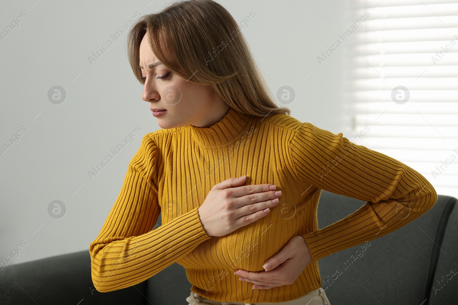 Photo of Mammology. Young woman doing breast self-examination at home