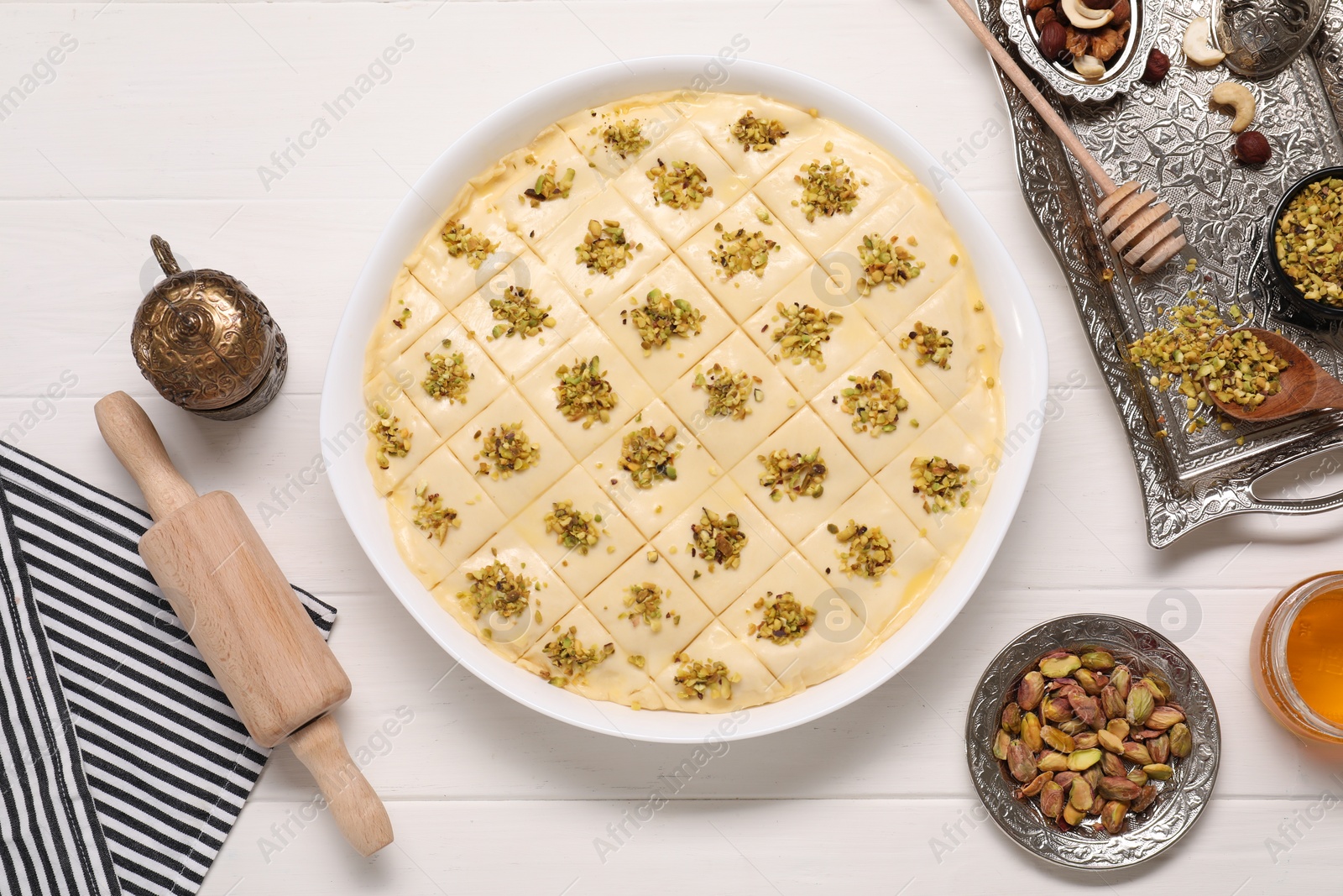 Photo of Making delicious baklava. Raw dough with ingredients on white wooden table, flat lay