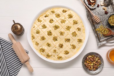 Photo of Making delicious baklava. Raw dough with ingredients on white wooden table, flat lay
