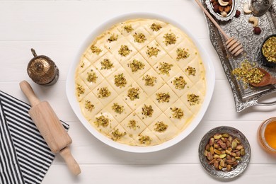 Making delicious baklava. Raw dough with ingredients on white wooden table, flat lay