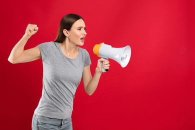 Photo of Young woman with megaphone on red background