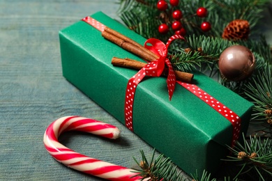 Christmas gift box, candy cane and festive decor on blue wooden table, closeup