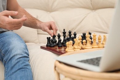 Photo of Man playing chess with partner through online video chat at home, closeup