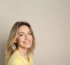 Portrait of happy young woman with beautiful blonde hair and charming smile on beige background. Space for text