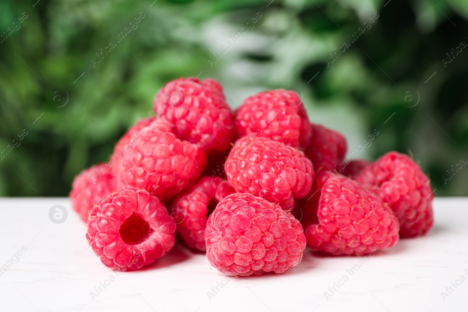 Photo of Delicious fresh ripe raspberries on white wooden table, closeup