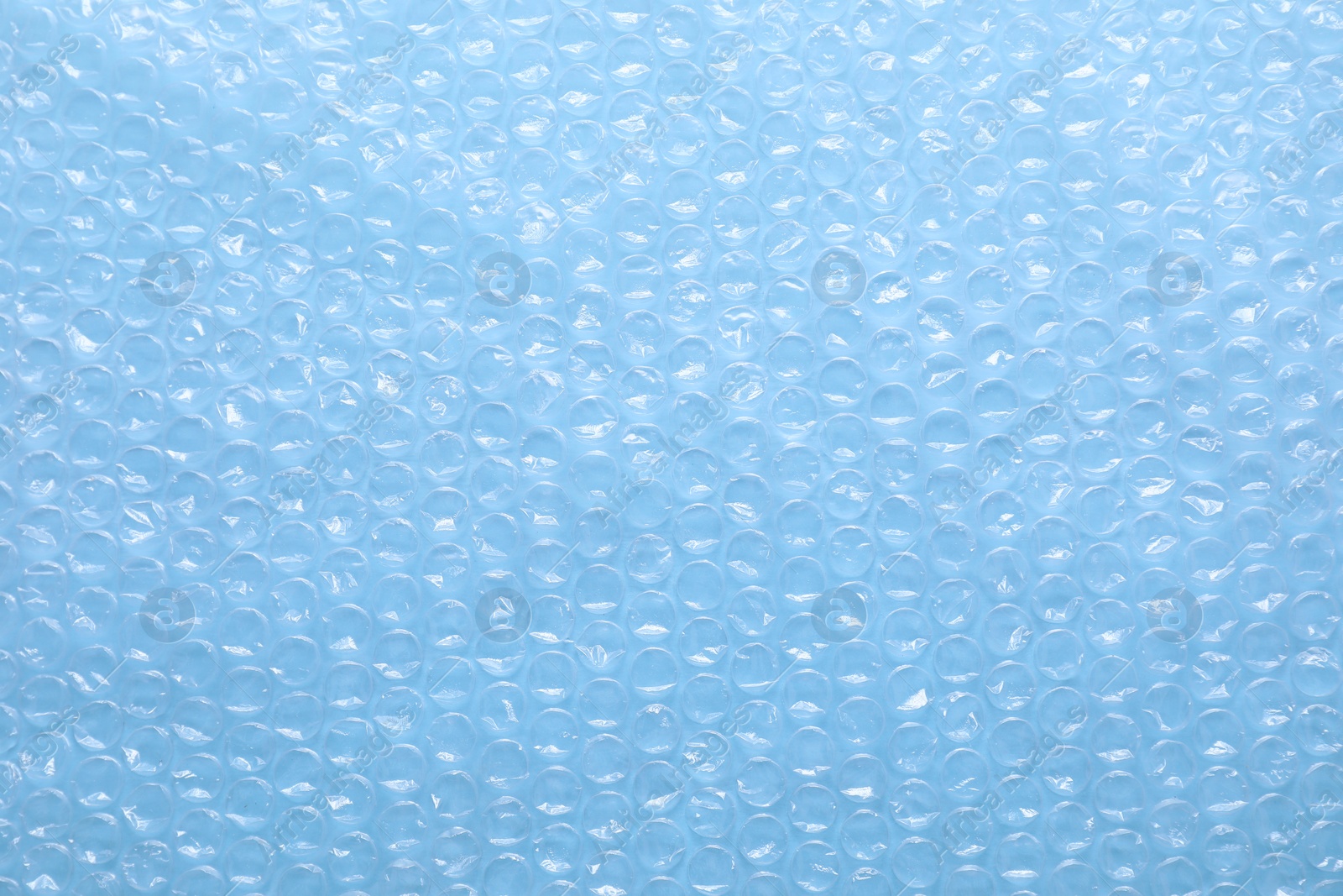 Photo of Transparent bubble wrap on light blue background, top view