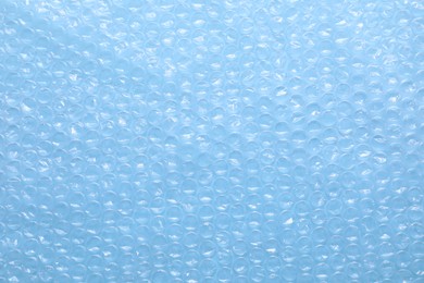 Photo of Transparent bubble wrap on light blue background, top view