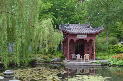 HAREN, NETHERLANDS - MAY 23, 2022: Beautiful view of oriental gazebo near pond in Chinese garden