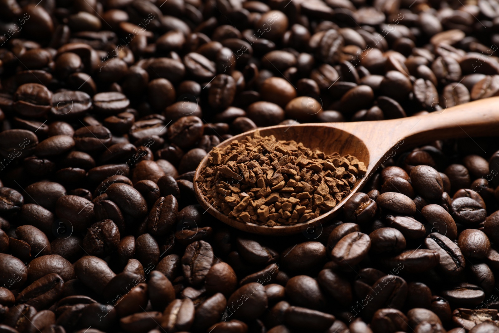 Photo of Spoon with instant coffee on roasted beans, closeup. Space for text