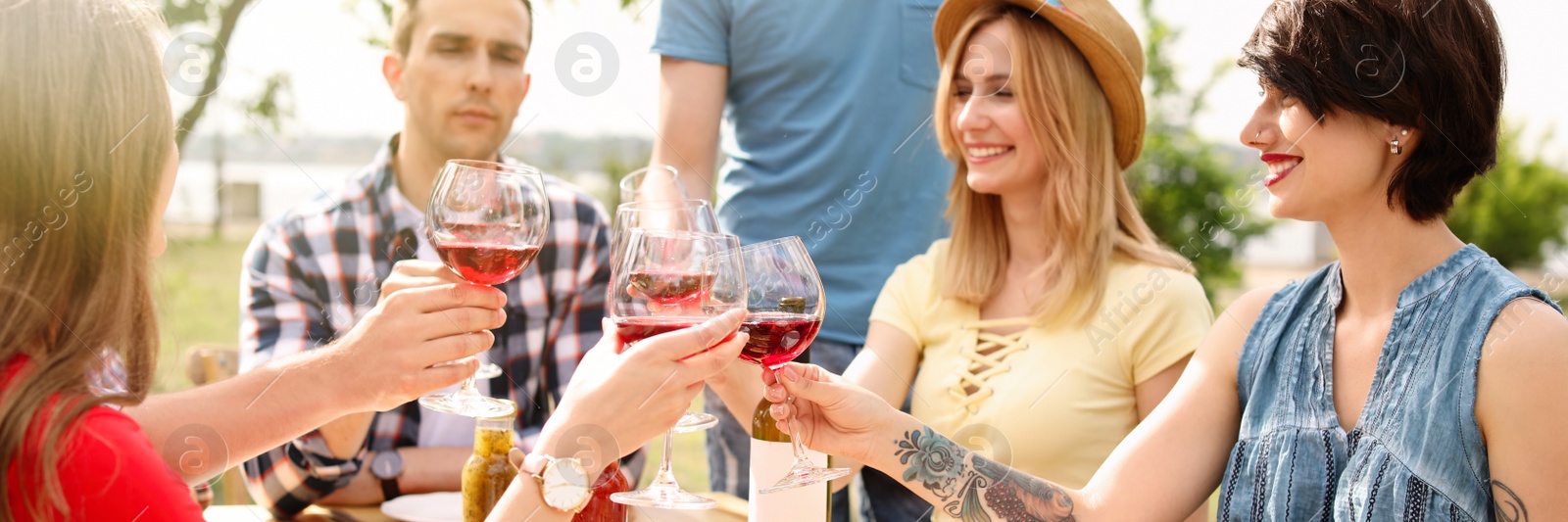 Image of Young people with glasses of wine at table outdoors. Banner design