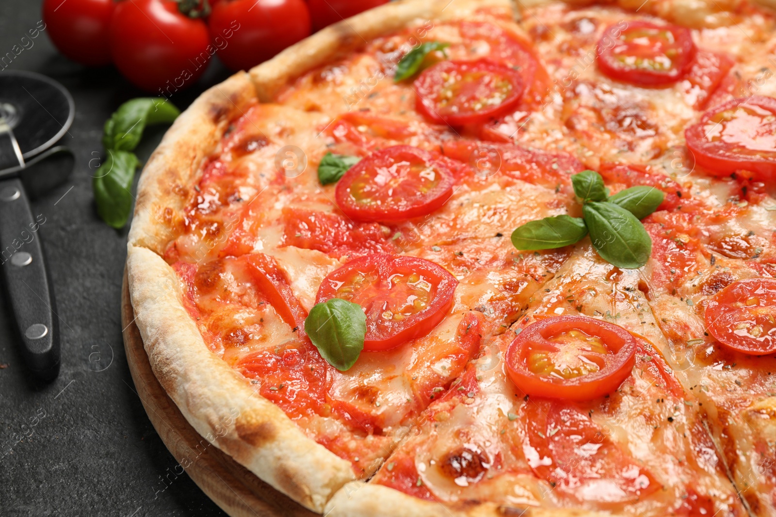 Photo of Delicious pizza Margherita and ingredients on dark grey table, closeup
