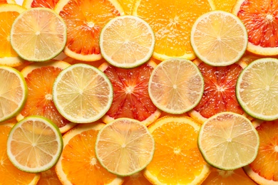 Photo of Slices of fresh citrus fruits as background, top view