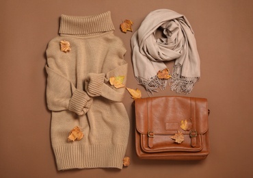 Photo of Flat lay composition with sweater and dry leaves on brown background. Autumn season