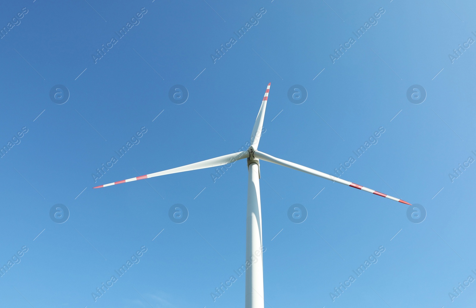 Photo of Modern wind turbine against blue sky, low angle view. Alternative energy source