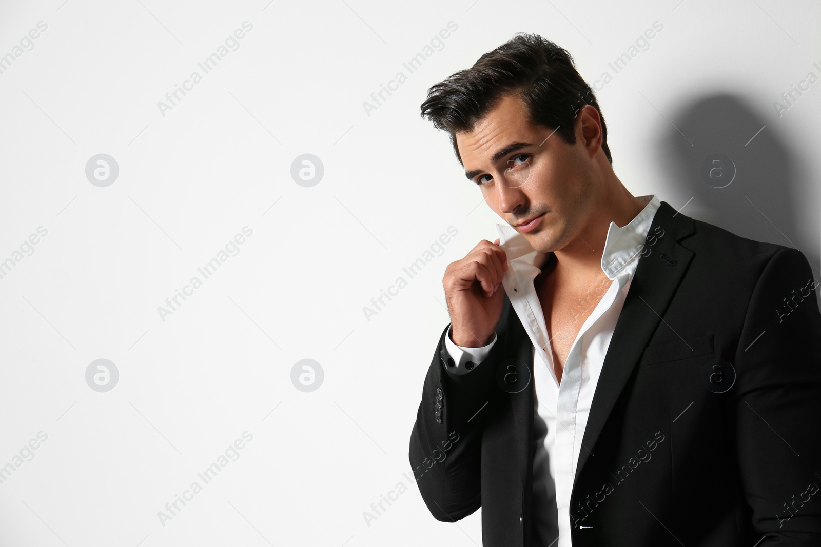 Photo of Handsome young man in elegant suit on light beige background. Space for text