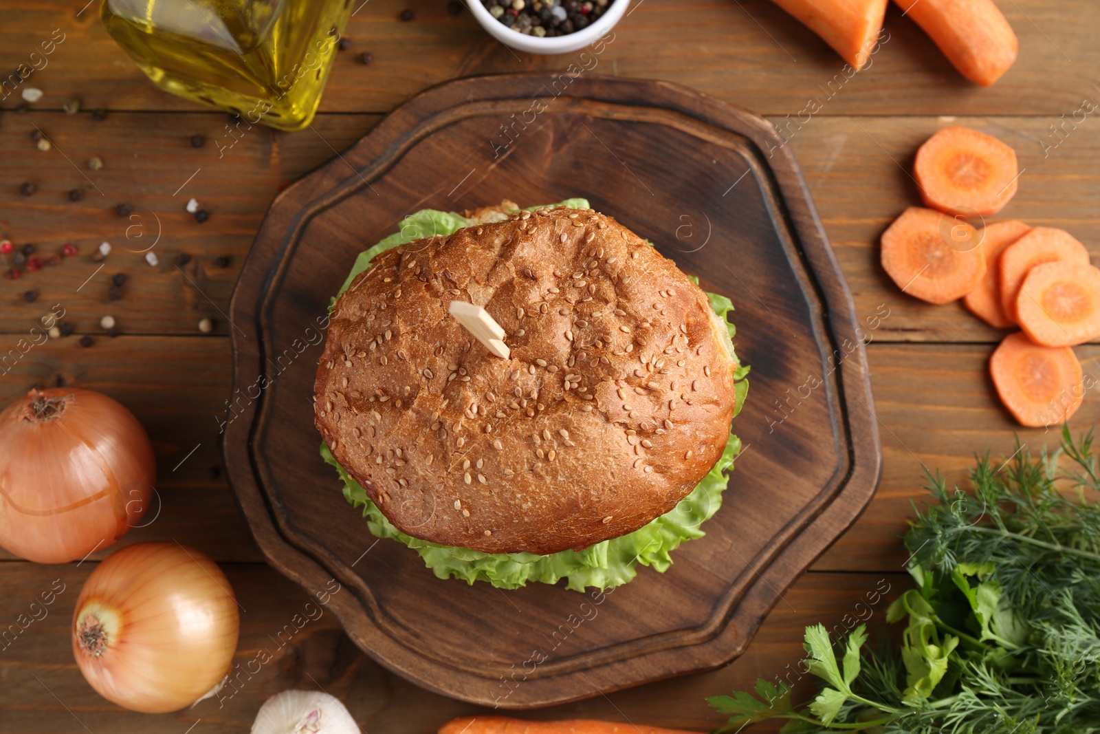 Photo of Delicious vegetarian burger and ingredients on wooden table, flat lay