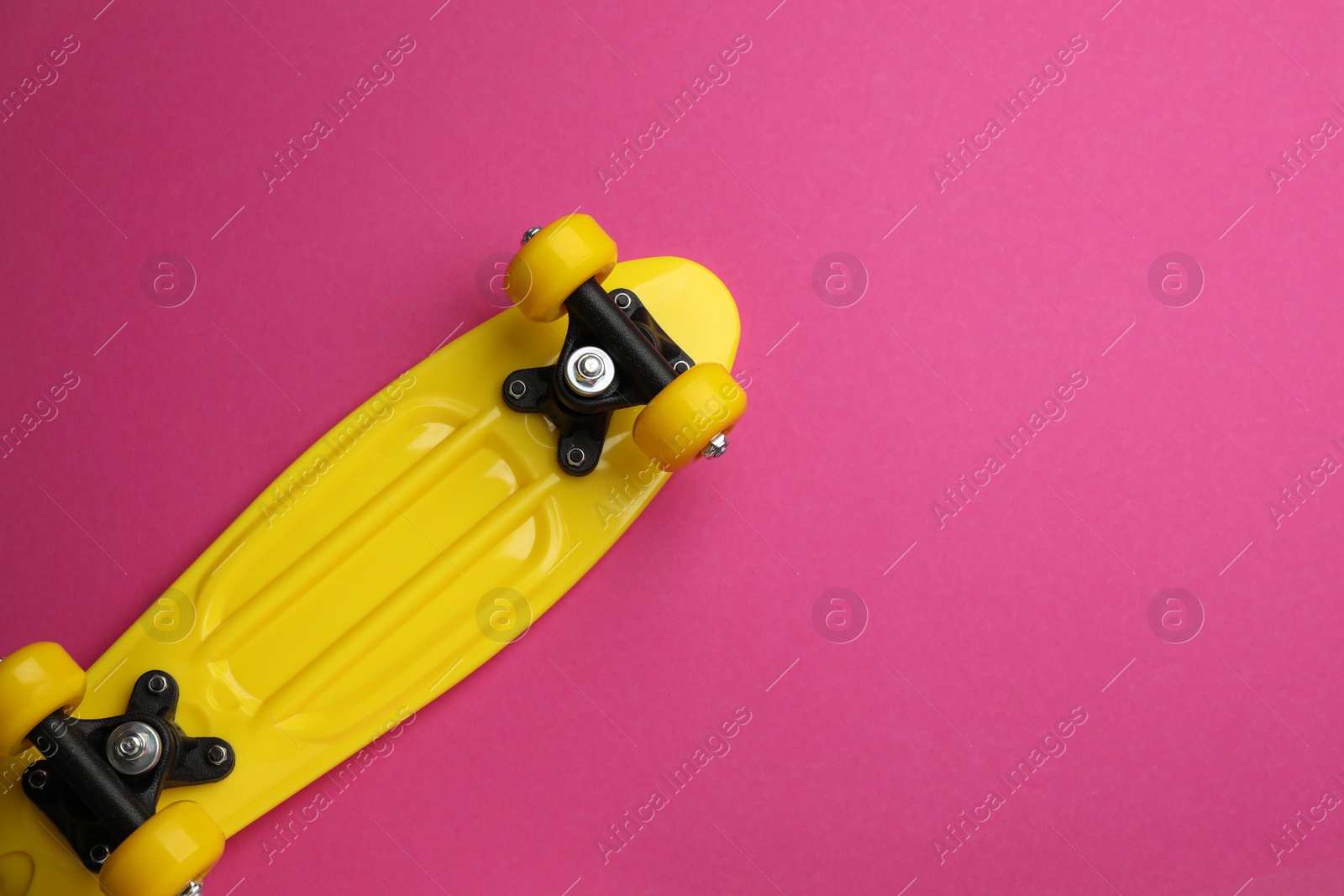 Photo of Skateboard on crimson background, top view. Space for text