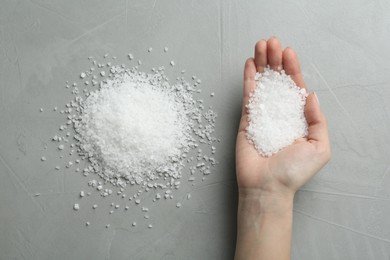 Woman with natural sea salt at grey table, top view