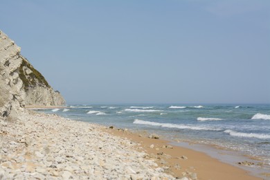 Photo of Beautiful view of sandy beach with rocks and sea. Summer vacation
