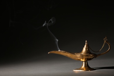 Photo of Aladdin lamp of wishes on table against dark background