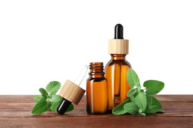 Photo of Bottles of essential oil and mint on wooden table against white background