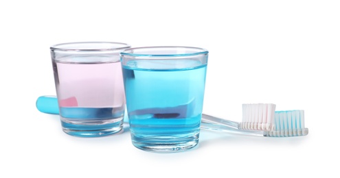 Photo of Glasses with mouthwash and toothbrushes on white background. Teeth hygiene