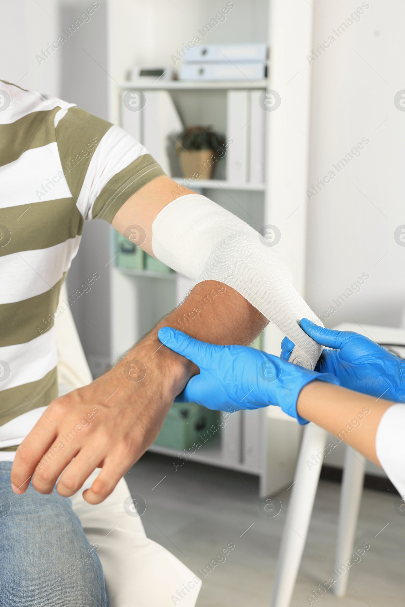 Photo of Doctor applying bandage onto patient's arm at hospital, closeup