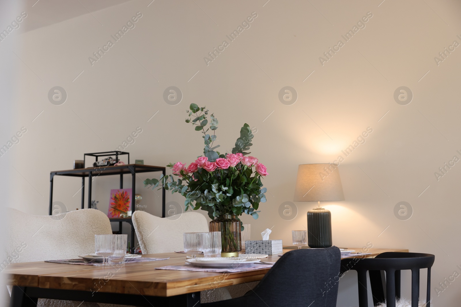 Photo of Beautiful table setting with bouquet in dining room. Roses and eucalyptus branches in vase