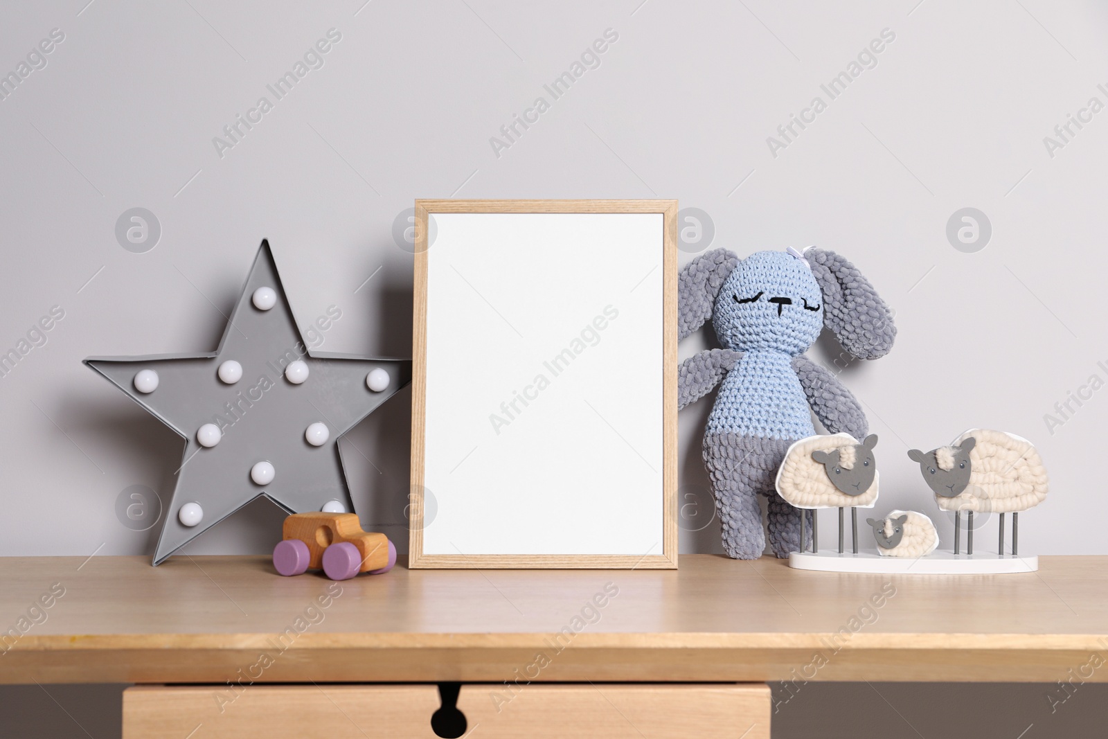 Photo of Empty square frame and different toys on wooden table